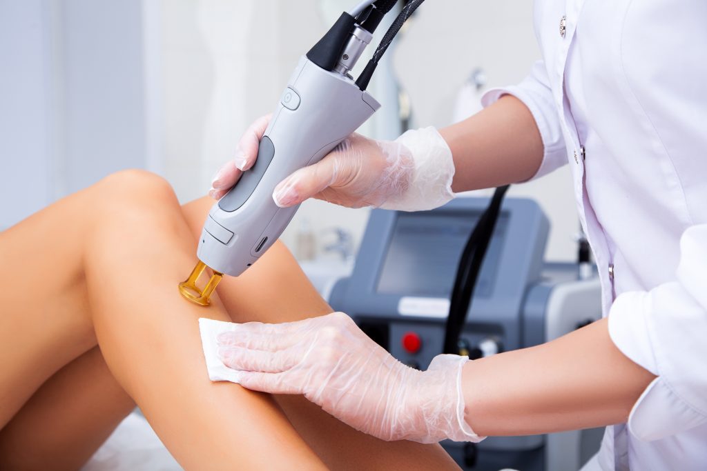 Une professionnelle épile les jambes d'une femme grâce à la technologie de l'épilation laser.